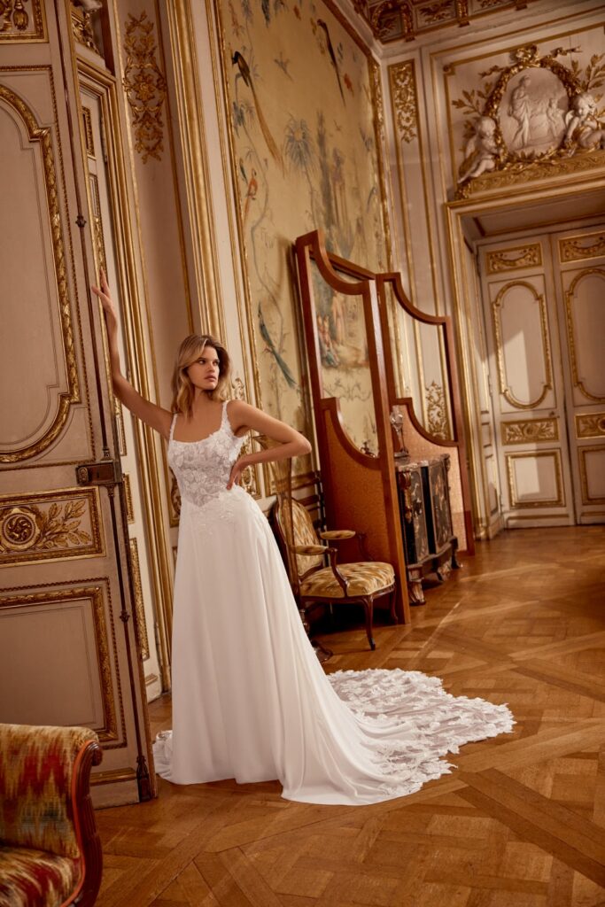 Eine Frau in einem weißen Brautkleid posiert in einem prunkvollen, eleganten Raum mit goldenen Akzenten und Wandmalereien.